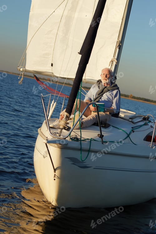 Preview: Vertical shot of relaxed retired man enjoying amazing view and relaxing, reading book while sitting