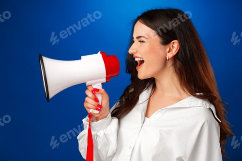 Preview: Young brunette businesswoman holding a megaphone against blue background
