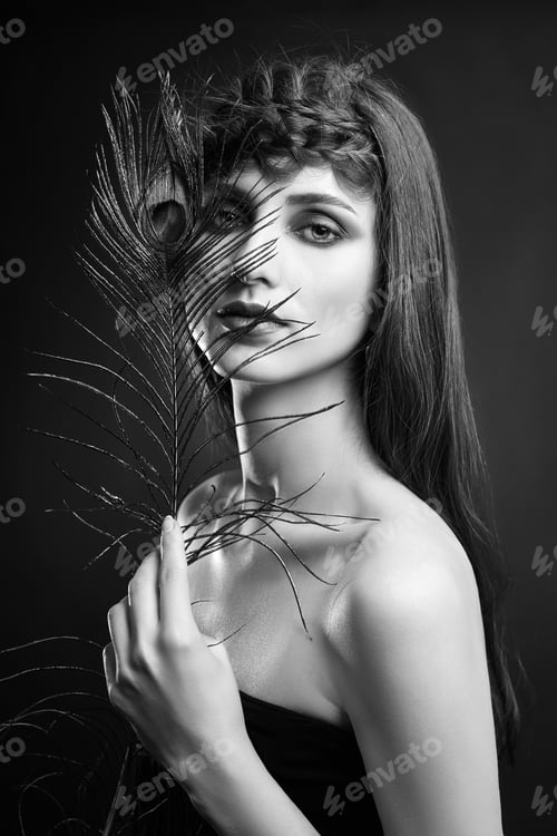 Preview: Eastern Arab woman with a peacock feather in her hands near her face. Beauty fashion makeup Arab