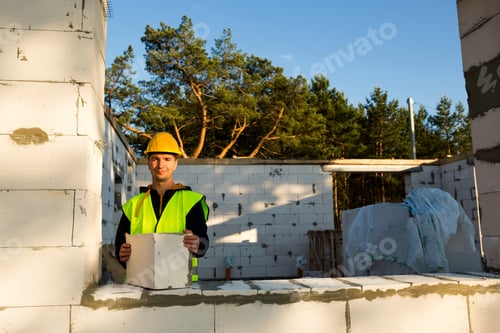 Preview: The builder holds a block of cellular concrete in his hands - the masonry of the walls of the house.