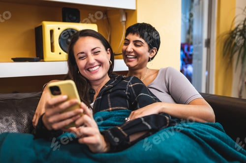 Preview: Lesbian couple on the sofa enjoying time together on social media