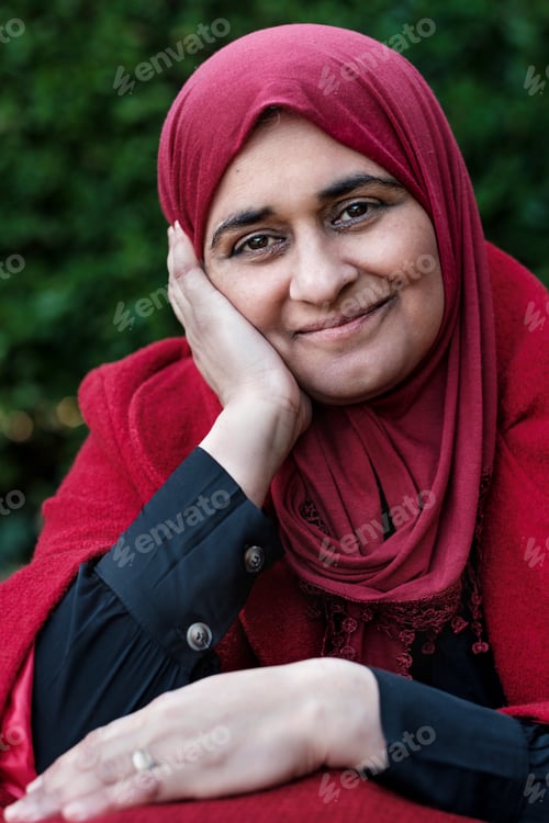 Preview: Muslim mature woman wearing hijab posing smiling in a red outfit.