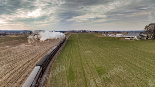 Preview: Vintage locomotive train chugging along railroad tracks in a scenic countryside setting