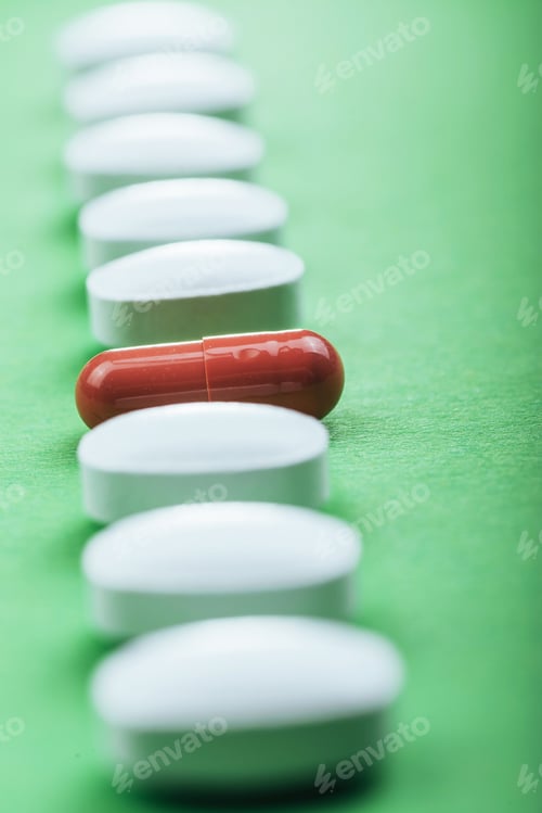 Preview: Medical white pills and brown capsules for the treatment and health care on a green background
