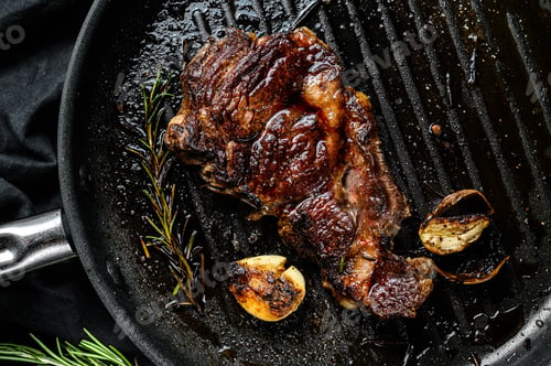 Preview: Rib eye steak on a grill pan. Grilled beef. Organic farm meat. Black background