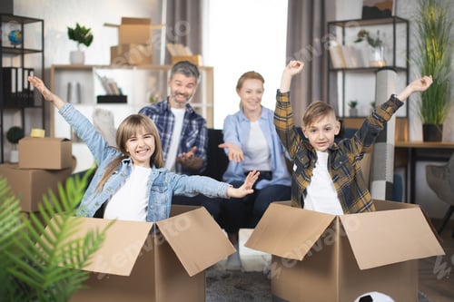 Preview: Happy kids playing in cardboxes while parents relaxing on couch
