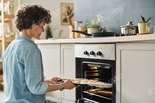 Preview: Woman using oven to bake buns