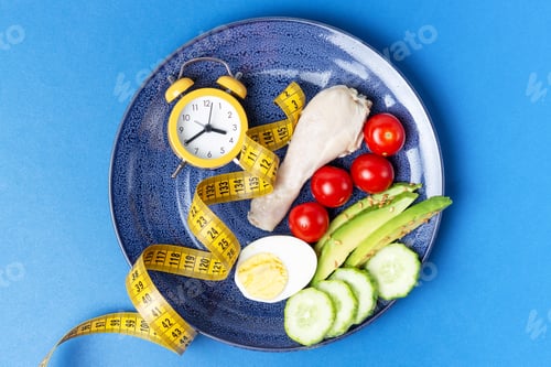 Preview: Plate with vegetables and yellow alarm clock on blue background