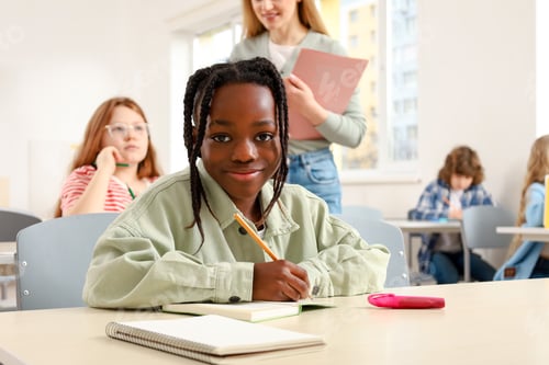 Preview: Happy African American boy sitting at the desk in classroom, looking at camera