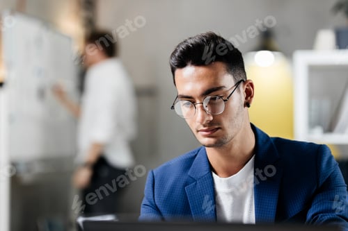Preview: Professional young architect in glasses dressed in blue checkered jacket works on the laptop in the