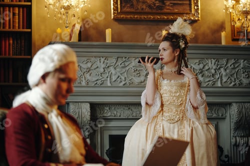 Preview: Caucasian Young Woman in Baroque Dress Holding Fan While Standing Indoors