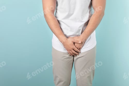 Preview: Young man with urological problems suffering from pain on color background