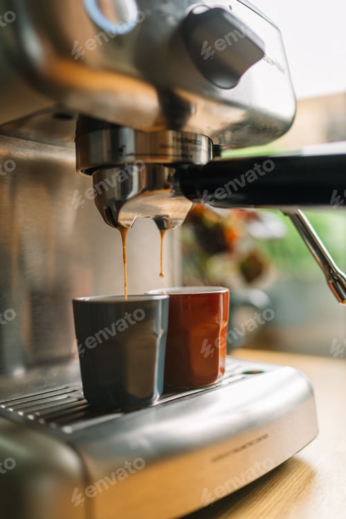 Preview: Close-up of an espresso machine brewing two cups of coffee in a cozy kitchen setting.