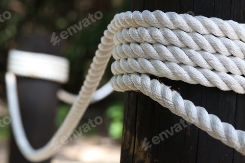 Preview: Close up of two brown wood posts with white thick rope tied around them