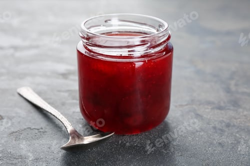Preview: Tasty homemade strawberry jam on grey table, closeup