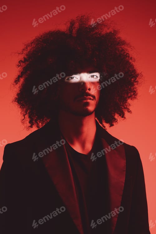 Preview: Fashion portrait of a man with curly hair on a red background, multinational, colored light, trendy