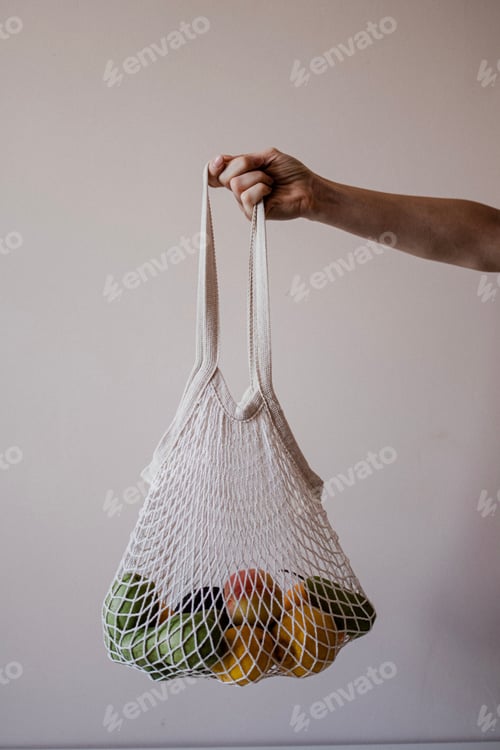 Preview: The girl is holding an eco-aware handbag full of different fruits. Ecological shopping bag.