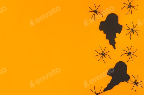 Preview: Happy Halloween! Black ghosts and spiders flat lay on orange background. Modern minimal border
