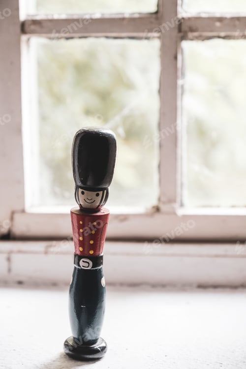 Preview: A wooden toy soldier standing on a windowsill with a blurred background.