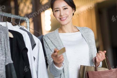 Preview: Mature Chinese woman with credit card in clothing store