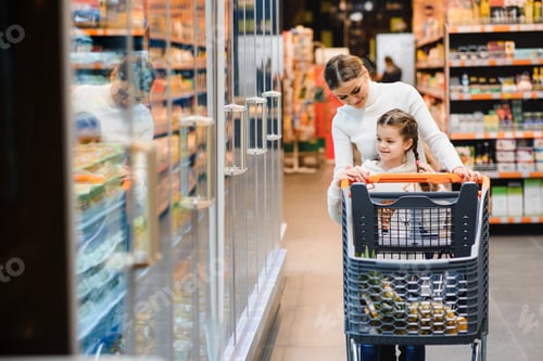 Preview: Family in the supermarket. Beautiful young mom and her little daughter smiling and buying food.