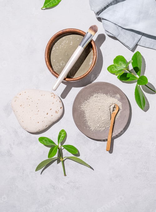 Preview: Handmade cosmetics. Organic clay in a bowl with a brush on a light background with shadow and leaves