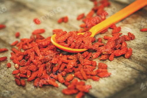 Preview: Goji Berries in a spoon on a wooden board.