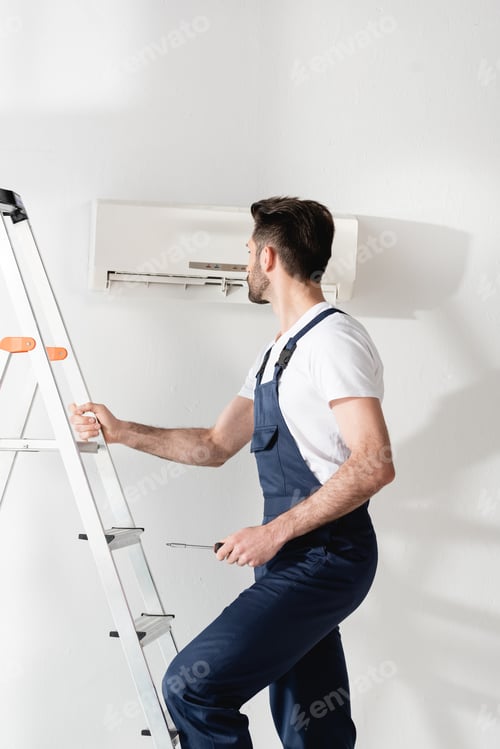 Preview: workman holding screwdriver while standing on stepladder near air conditioner
