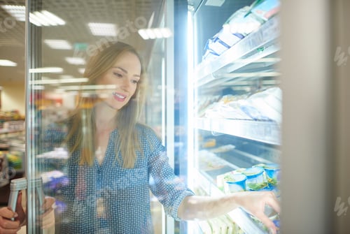 Preview: Female shopper reaching product from freezer
