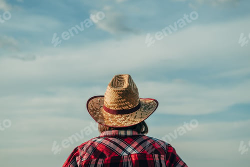 Preview: Rear view of female farmer wearing straw hat standing in field