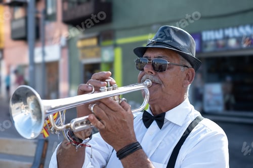 Preview: Portrait of jazz artist outdoors concert. Elderly man with black hat playing a trumpet in the street