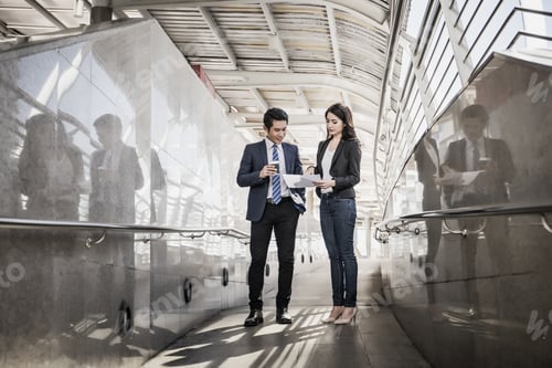 Preview: Business colleagues take a look at the work in the tablet while walking to the office together.