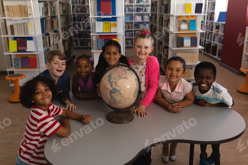 Preview: Front view of happy schoolkids with globe looking at camera in school library