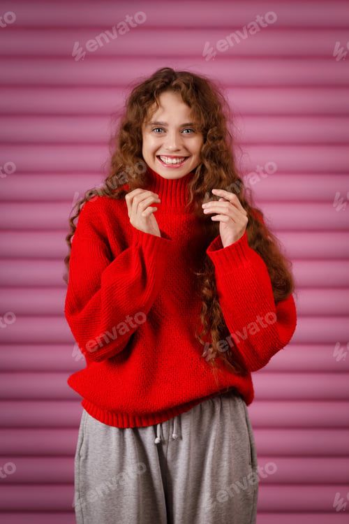 Preview: smiling young adult woman wearing winter red sweater indoors looking at camera with joyful smile.