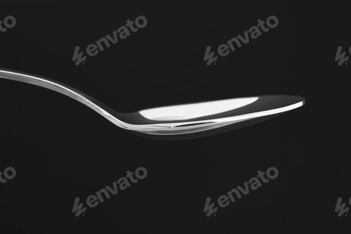 Preview: Stainless steel spoon over a black background. Cutlery