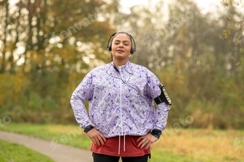 Preview: Healthy woman listening to music in the park, stretching and keeping fit