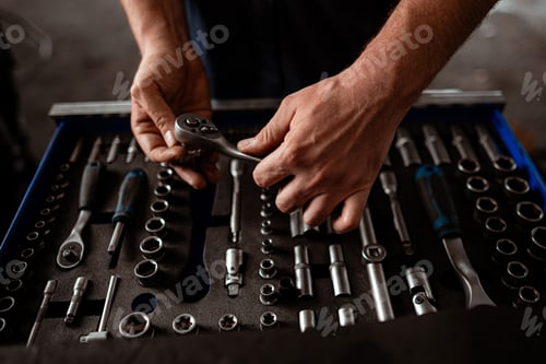 Preview: Hands work with a tool from a set in a garage during the day