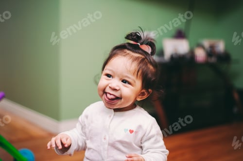 Preview: Cute diverse toddler girl at home making happy expression on face