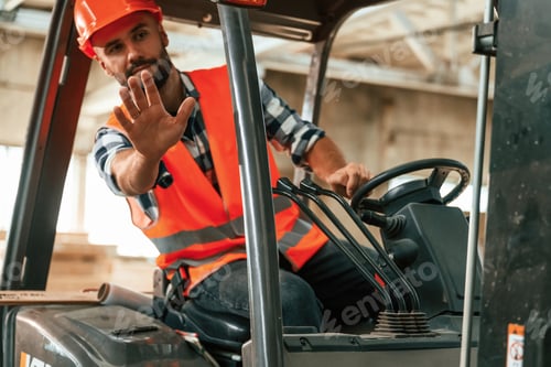 Preview: Driving the forklift. Industrial worker in wooden warehouse