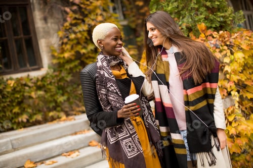 Preview: Young multiethnic women listen music at autumn day