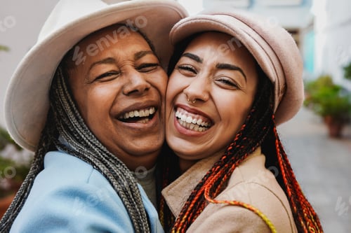 Preview: Happy african mother and adult daughter hugging together during winter vacation in the city