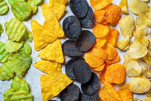 Preview: Different types of colored potato chips, gray background. Fast food concept.