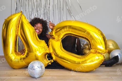 Preview: African woman in a 40 birthday party playing with 40 birthday golden balloons.