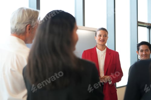 Preview: Diverse business team in a modern office meeting, with a woman presenting in a red blazer