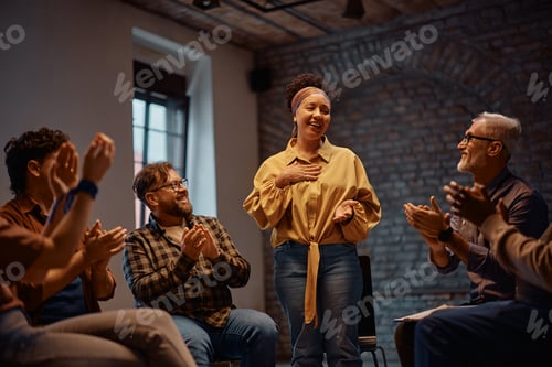 Preview: Happy woman receiving applause from participants of group therapy at mental health center