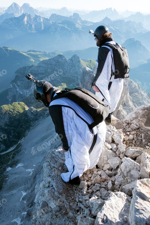 Preview: Two male BASE jumpers preparing to launch from mountain, Dolomites, Italy