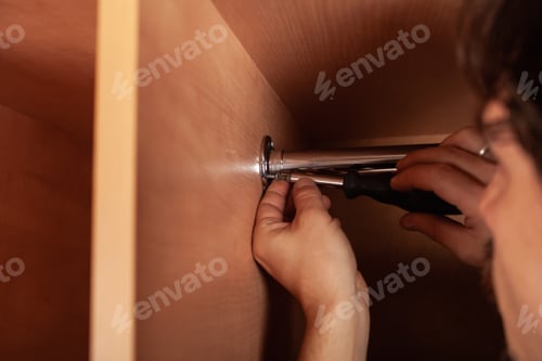 Preview: A man twists a pipe for a hanger in a closet with a screwdriver. to hang clothes