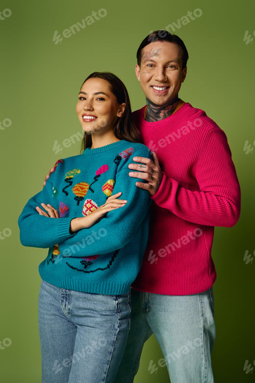 Preview: Young couple in colorful sweaters stands together against a vibrant green backdrop