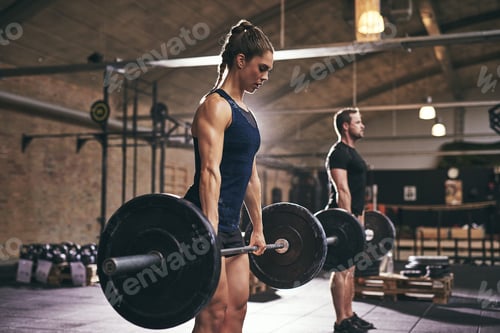 Preview: Sportive serious people lifting barbells in gym