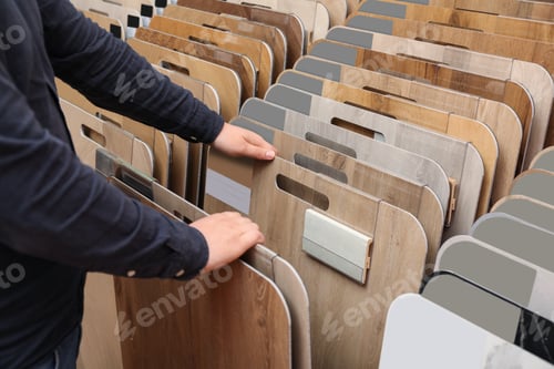 Preview: Man choosing wooden flooring among different samples in shop, closeup